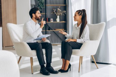 Mutlu, gülümseyen profesyonel bir doktorun portresi, çekici bir kadınla konuşan, modern bir ofiste oturan bir psikolog. İletişim, terapi konsepti