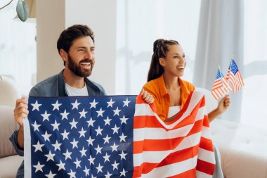 Mutlu, heyecanlı İspanyol erkek ve kadın portresi, ellerinde Amerikan bayrakları tutan destekçiler evde oturarak seçim sonuçlarını kutluyorlar. Bağımsızlık Günü kavramı