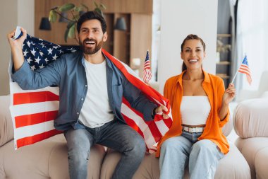 Çekici pozitif Latin çift, ellerinde Amerikan bayrağı tutan arkadaşlar evde oturan başkanlık seçimlerinde zaferle seviniyorlar. Kutlama kavramı, bağımsızlık günü