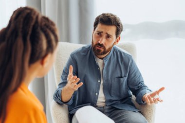 Profesyonel doktor portresi, psikolog üzgün, mutsuz bir adamla konuşuyor, modern ofiste oturuyor. İletişim, terapi konsepti