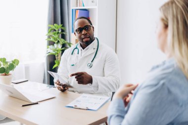 Gözlüklü Afro-Amerikalı doktor, klinikteki kadın hasta için röntgen filmi çekiyor. Sağlık, tıp konsepti