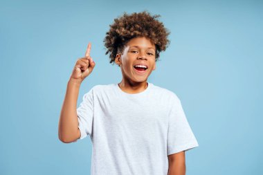 Kıvırcık saçlı, gülümseyen, otantik Afro-Amerikan çocuğun kamera karşısında fikir sahibi olduğunu gösteren portresi. Beyin fırtınası, reklam konsepti