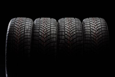 Kışın sürüş için güvenlik ve performansı vurgulayan koyu bir arka planda dört adet kış lastiği kapatın.