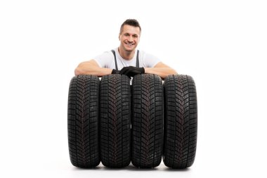 Gülümseyen tamirci, stüdyo çekiminde dört araba lastiğine dayanan eldivenler giyiyordu.