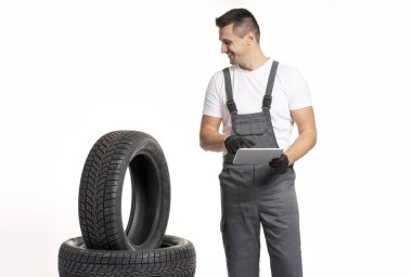 Dijital tablet kullanan ve araba lastiklerini inceleyen tamirci, uygun çevrimiçi lastik ve satış hizmeti sunuyor