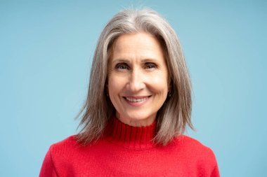 Mutlu, gülümseyen, gri saçlı yaşlı kadın portresi, modellik yapan, kameraya bakan, mavi arka planda izole edilmiş. Alışveriş, reklam konsepti.