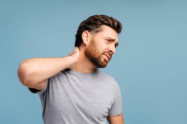 Üzgün, sakallı, boynu ağrıyan bir İspanyol 'un portresi. Mavi arka planda soyutlanmış bir şekilde başka tarafa bakıyor. Tedavi, sağlık hizmeti kavramı