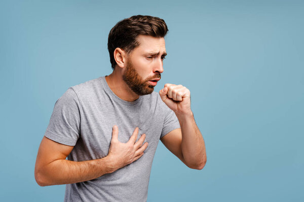 Portrait of sick, upset Hispanic man cough, having virus, cold isolated on blue background. Treatment, health care concept