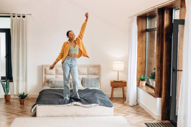 Mutlu Afrikalı kadın kutlama yapıyor, dans ediyor, hafta sonu evde yatak odasında ayakta duruyor. Yaşam tarzı kavramı