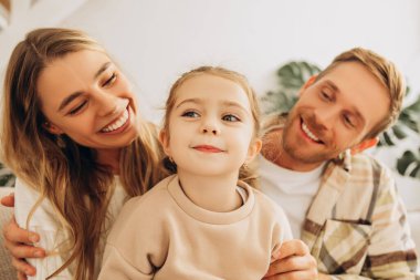 Evdeki oturma odasında oturan güzel aile portresi, oturma odasında oturan küçük kız ve ebeveyn. Ebeveynlik, çocukluk kavramı