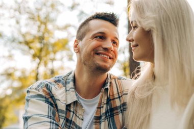 Aşık mutlu bir çiftin portresi, güzel bir kadın ve erkek birbirine sarılıyor, dışarıda, parkta birbirlerine bakıyorlar. İlişki, sonbahar, flört kavramı