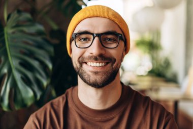 Gülümseyen mutlu Latin adamın portresi sarı şapkalı ve şık gözlüklü, kameraya bakan, yakın plan. Diş, görme konsepti