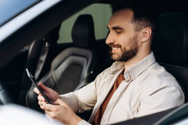 Kendine güvenen, gülümseyen, başarılı sakallı adam, dijital tablet tutan iş adamı, online alışveriş, kısa mesaj, yeni arabada oturan. Kiralama, sigorta, ulaşım konsepti
