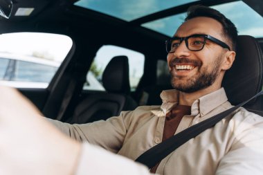 Kendine güvenen orta yaşlı bir işadamının portresi şık gözlükler takıyor, yeni bir araba sürüyor, direksiyon tutuyor, başka tarafa bakıyor. Ulaşım, sigorta kavramı