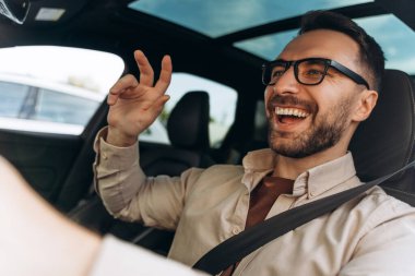 Gülümseyen, orta yaşlı, gözlüklü ve yeni araba sürerken eğlenen bir adamın portresi. Araç kavramı