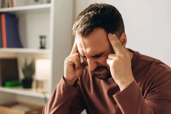 Stresli Latin işadamı başını tutuyor, gözleri kapalı, ofis ortamında acı ve yorgunluk gösteriyor. Hasta sakallı adamın kötü haberi var. Sağlık hizmeti kavramı