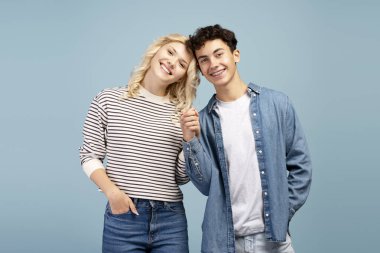 Mutlu, çekici bir çift, gülümseyen erkek arkadaş ve kız arkadaş el ele tutuşuyorlar, mavi arka planda tek başlarına kameraya bakıyorlar. İlişki, aşk kavramı