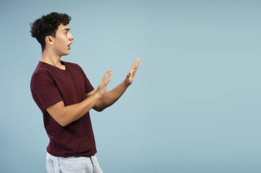 Endişeli, korkmuş genç bir çocuğun portresi, fotokopi odasına bakıyor, mavi arka planda tek başına duruyor. Reklam, alışveriş konsepti