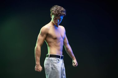 Siyah arka planda tek başına duran çıplak gövdeli, güçlü ve yakışıklı bir gencin portresi. Spor, sağlık hizmeti kavramı