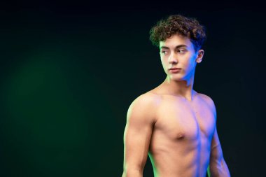 Ciddi, dalgın, çıplak gövdeli bir gencin portresi. Siyah arka planda tek başına duran fotokopi alanına bakıyor. Reklam kavramı