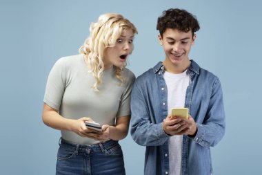 Diş teli takan mutlu, heyecanlı kız ve oğlan, cep telefonu tutan gençler, para kazanmak, sohbet etmek, mesaj atmak, mavi arka planda tek başına durmak. Sosyal medya kavramı