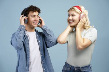 Telli çekici bir çocuk portresi ve kablosuz kulaklıkla müzik dinleyen sarışın kız mavi arka planda tek başına duruyor. Çevrimiçi teknoloji kavramı