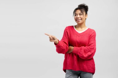 Neşeli genç bir kadın beyaz bir arka planda gülümserken ilginç bir şey sunuyor.