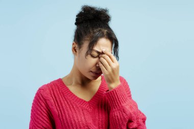 Burnuna dokunan ve arka planda sinüs ağrısı çeken genç bir kadının stüdyo portresi.