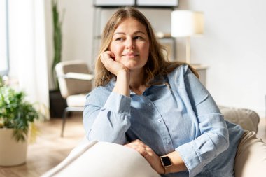 Orta yaşlı güzel bir kadın ve dinlenen bir kadın rahat bir kanepede hafta sonunun tadını çıkarıyor. Yaşam tarzı kavramı