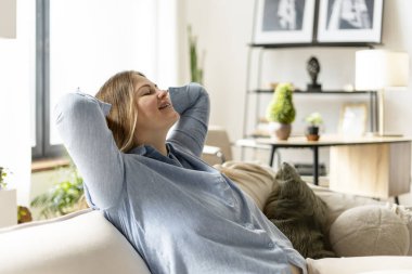 Evde rahat bir kanepede uzanıp dinlenirken, el ele tutuşan rahat bir kadın. Yaşam tarzı, yerli kavram