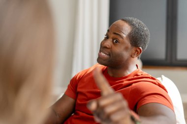 Evdeki oturma odasında üzgün, Afro-Amerikan bir adamın bir kadınla konuşmasının portresi. Olumsuz duygular, sorunlar, kavga ve boşanma