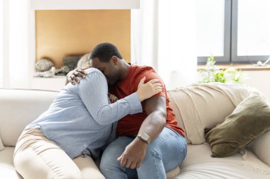 Evdeki oturma odasında kanepede oturup kucaklaşan romantik çok ırklı çiftin portresi. Aile, ilişkiler konsepti