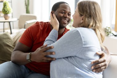 Kanepede dinlenen, kucaklaşan ve evde rahatlayan, birbirine bakan, çok kültürlü, romantik bir çift. Aile, ilişkiler konsepti