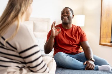 Evde oturan sağır dilli çok ırklı bir çiftin portresi. Hareketli iletişim kavramı