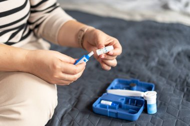 Evde kan şekeri seviyesini ölçmek için parmağına neşter takan bir kadının kesilmiş fotoğrafı. Ev sağlığı önleme. Sağlık hizmeti, tıp konsepti