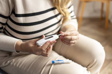 Glukometresi olan ve evinde kan şekerini ölçen iri yarı bir kadın. Ev sağlığı önleme. Sağlık hizmeti, tıp konsepti