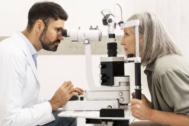 Bir göz hastalıkları kliniğinde muayenede tıbbi bir cihaz kullanarak hastanın gözlerini muayene etmek, görüş ve göz sağlığının eksiksiz değerlendirilmesini sağlamak,