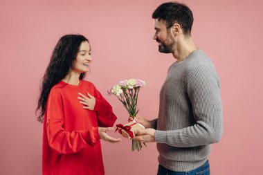 Mutlu adam pembe arka planda sürpriz bir kadına bir buket çiçek ve hediye veriyor. Özel bir olayı sevgi ve sevgiyle kutluyor. Kutlama konsepti
