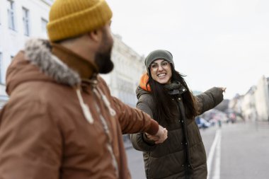 Neşeli genç bir kadın sokakta yürürken erkek arkadaşının elini tutuyor ve ona ilginç bir şey gösteriyor. Kış tatilinde yeni bir şehirde hafta sonu kaçamağının tadını çıkarıyor.