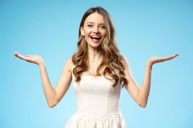 Mutlu kadın elleriyle bir şey gösteriyor ve mavi arka planda gülümsüyor. Reklam konsepti. Reklam kavramı