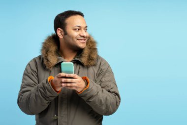 Kışlık palto giyen Hintli adam akıllı telefon kullanıyor ve mavi arka planda gülümseyerek başka tarafa bakıyor. Bu da hoş sohbetler yaptığını ya da ilginç içeriklere baktığını gösteriyor. Reklam kavramı