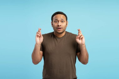 Umut dolu bir adam umut ediyor ve bir dilek diliyor, parlak mavi bir arkaplanda iyi şanslar diliyor, olumlu bir sonuç için beklenti ve arzusunu ifade ediyor.