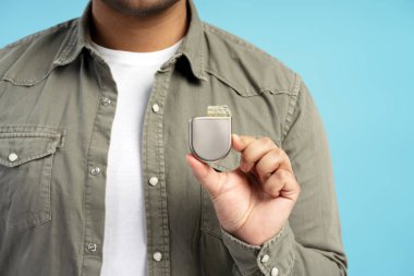 Kalp pili tutan bir adamın yakından görüntüsü, kalp sağlığı ve hasta bakımını geliştirmek için tasarlanmış tıbbi teknolojideki olağanüstü gelişmeleri vurguluyor.