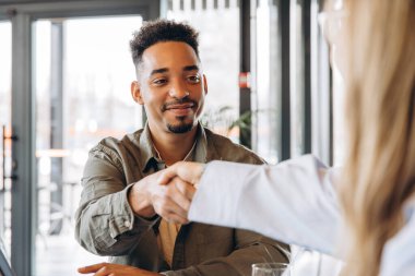 Modern bir kafede el sıkışan iki iş adamı başarılı bir ortaklığı kutlarken bir yandan da sıradan bir ortamın keyfini çıkarıyorlar.