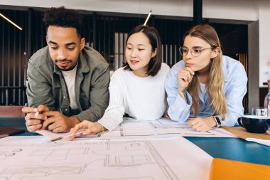 Üç genç mimar bir plana dayanıyor ve modern bir ofiste takım çalışması ve mimari tasarım alanında işbirliği sergileyen bir projeyi tartışıyorlar.