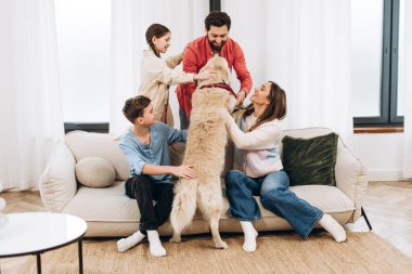 Neşeli aile evlerinde birlikte vakit geçirir, rahat bir kanepede dinlenir ve sevgili Golden Retriever 'larını okşar, sıcak bir atmosferi destekler.