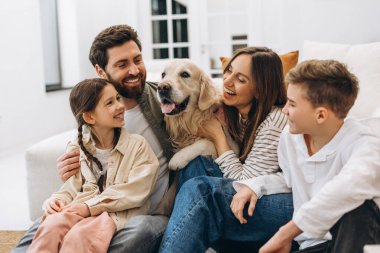 Aileler birlikte güzel vakit geçiriyorlar. Sevgili Golden Retriever 'larıyla evlerinde kucaklaşıp gülüyorlar. Yürek ısıtan bir sevgi ve bağ sahnesi yaratıyorlar.
