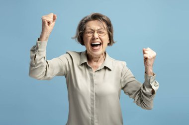 Neşesini ve zaferini ifade eden mest olmuş olgun bir kadın, başarısını yumruklarıyla ve canlı bir gülümsemeyle kutluyor.