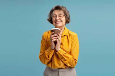 Neşeli, olgun iş kadını. Tek kullanımlık bardakta taze kahve kokusu alıyor. Gözleri kapalı ve gülümsüyor.