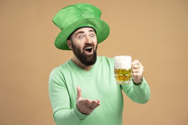 Yeşil cüce şapkalı sakallı adamın Aziz Patrick gününü kutlamak için bir bardak bira içmesine şaşırdım.